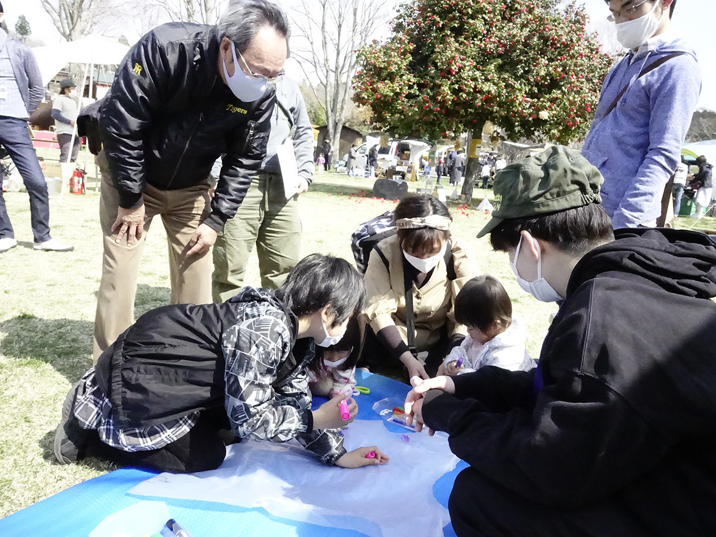 静岡大学学生防災ネットワークのメンバー（手前右）に教わりながら防寒具作りに挑戦する来場者